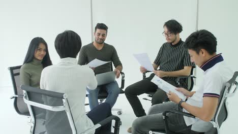 young creative business team brainstorming sharing new ideas in a circle around them on chairs