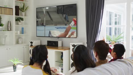 Composite-of-happy-family-sitting-at-home-together-watching-athletics-high-jump-event-on-tv