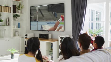 행복 한 가족 이 집 에서 함께 앉아서 tv 에서 육상 하이 점프 대회 를 시청 하고 있다