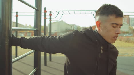 sporty man stretching shoulders on workout playground