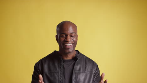 head and shoulders studio portrait of smiling and laughing mature man against yellow background 7