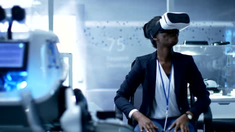 young black female virtual reality engineer/ developer wearing vr headset creates content. she's alone in a modern laboratory/ research center.