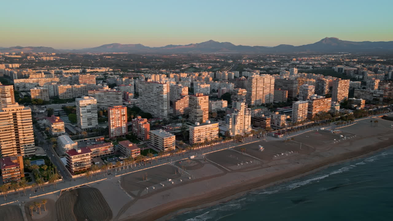 Aerial view of the beach and the buildings along the coastline in Alicante, Spain at sunset