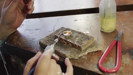 biracial female worker shaping ring with blowtorch in workshop in slow motion