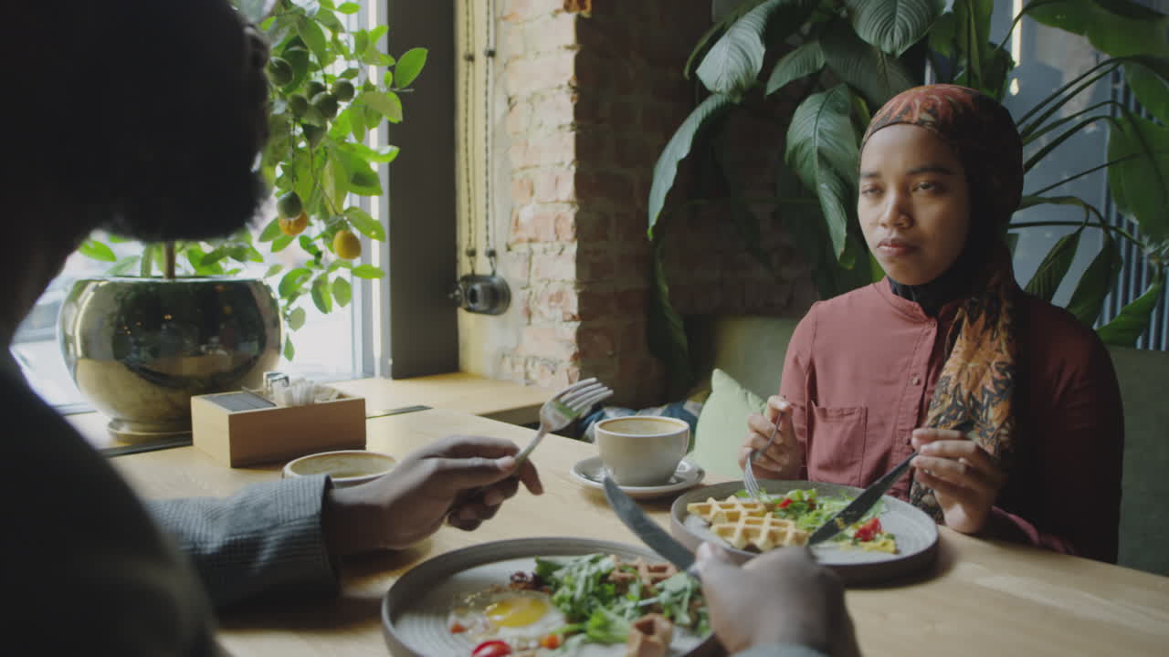 Muslim Woman Talking with Colleague over Lunch in Cafe