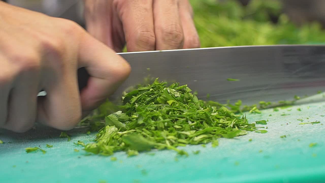 Close up on cook's hands cutting parsley SLOWMOTION 100fps