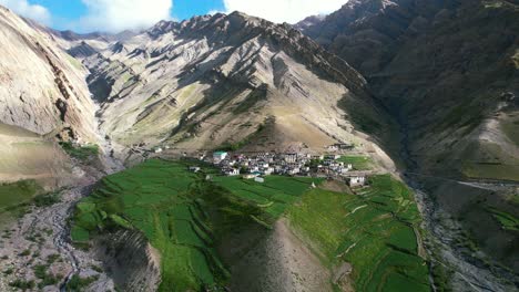 aerial-dolly-zoom-out-of-Mud-Village-in-the-remote-mountains-of-Pin-Valley-on-sunny-day-with-lush-green-ricefields-and-farmland