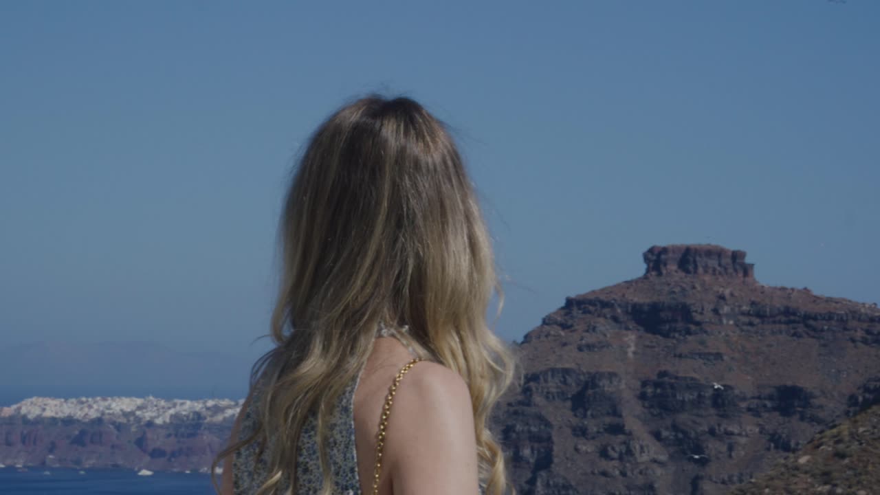 Woman with umbrella enjoying the cliffside view of Santorini in summer, Fira, Greece