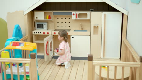 3-year-old girl toddler in playroom toy kitchen