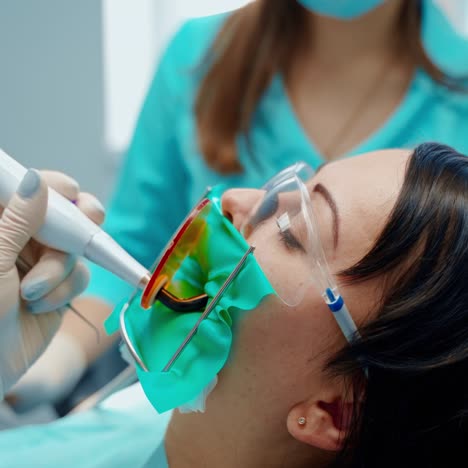 dental treatment. woman treats her teeth in clinic. stomatologist's hands in gloves holding modern medical equipment in patient's mouth. close-up.