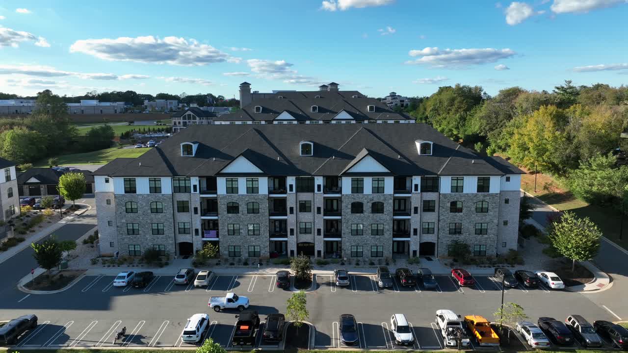 Luxury apartment blocks with parking cars during sunset time. New developed housing area with colorful trees in autumn. Suburb district of american town. Wide shot. Descend drone shot