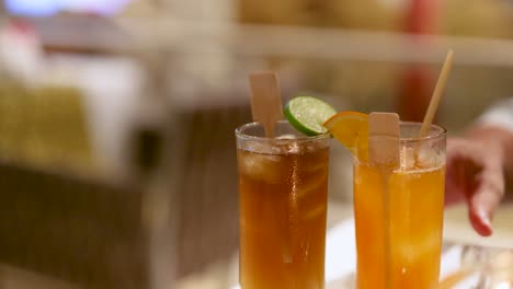 hand serving colorful cocktails garnished with citrus slices and ice cubes