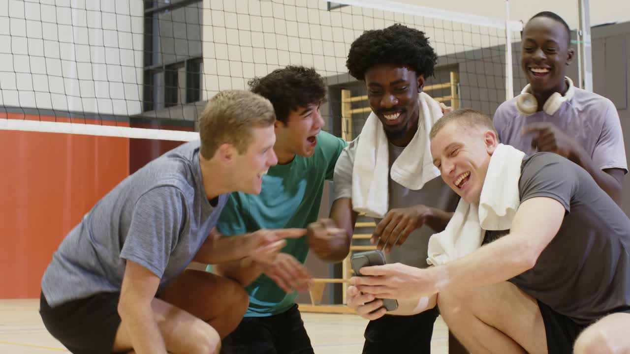 Ein diverses Männerteam, das nach dem Ball greift, macht ein Selfie mit dem Handy, überprüft das Bild und stößt auf dem Spielfeld die Fäuste zusammen.