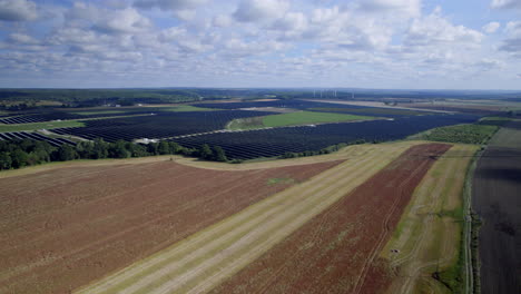 aerial view of large scale solar farm seen in background next to rural farmland