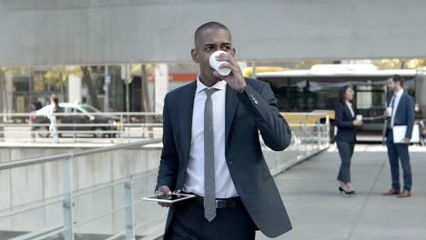 Young-businessman-with-paper-cup-and-tablet-pc