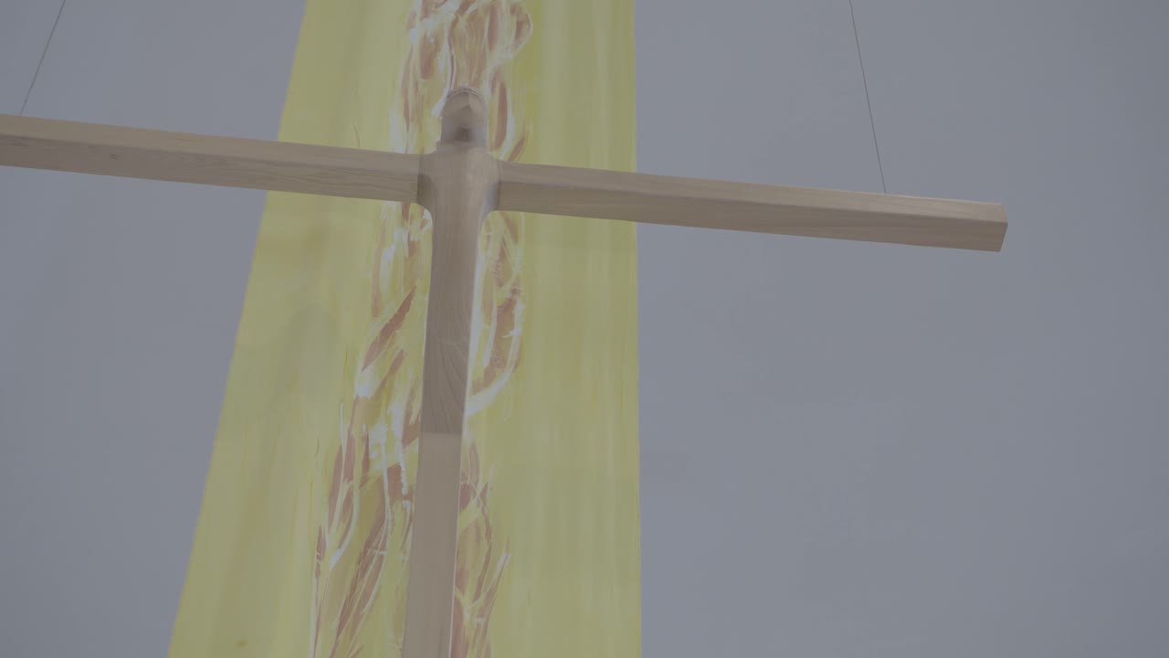 Abstract wooden cross in front of a yellow banner in a church at Easter time, close-up
