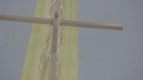 abstract wooden cross in front of a yellow banner in a church at easter time, close-up