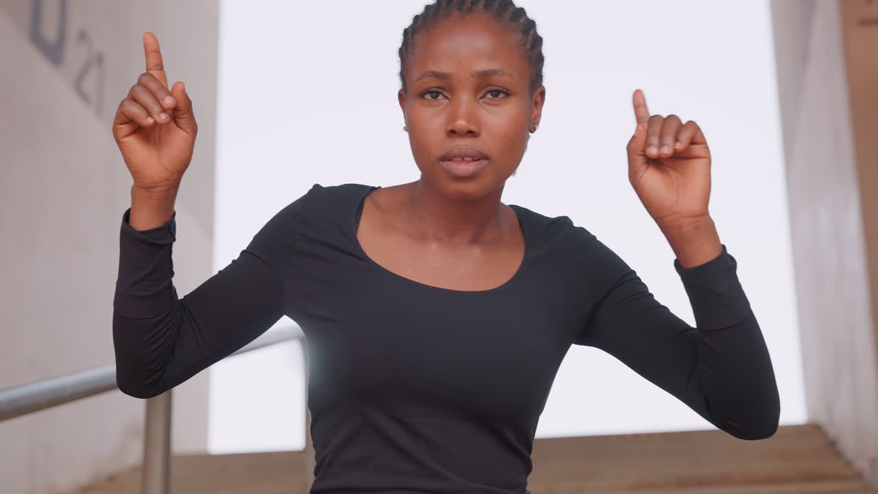 Donna mostra un'energica danza sulle scale. Donna dinamica che esibisce gesti vivaci durante la prova di danza sulle scale. Danzatrice entusiasta che esprime gioia con movimenti energici su una rampa di scale