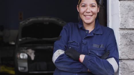 retrato de una mecánica con los brazos cruzados sonriendo en una estación de servicio de automóviles