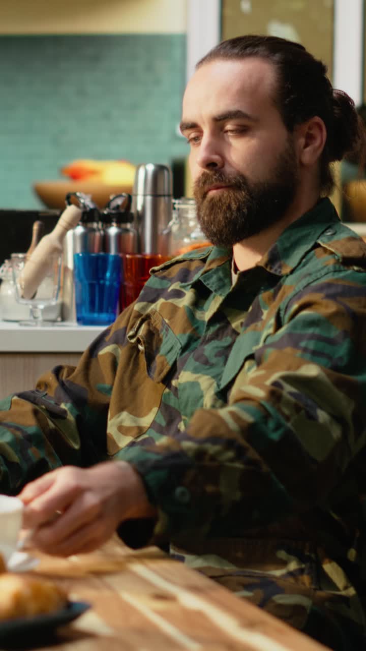 Vertikal video: Soldat i militæruniform tilbringer en stille morgen i køkkenet