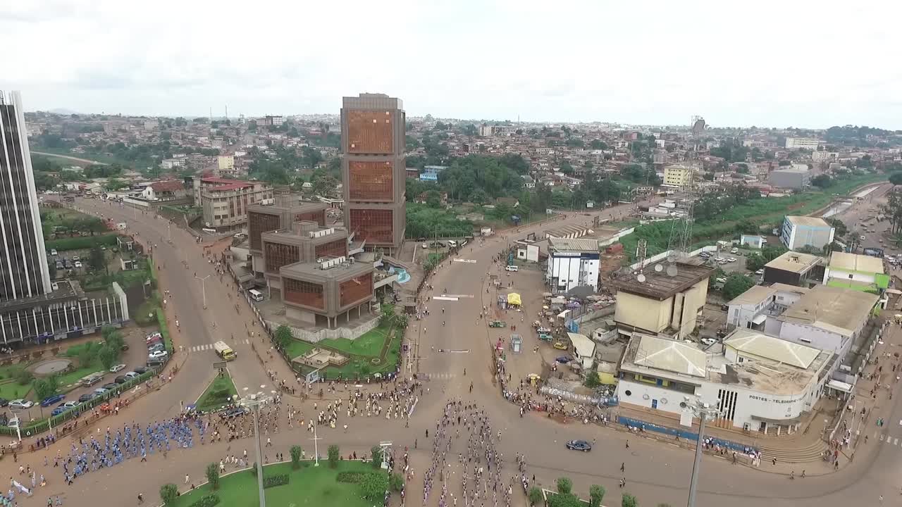 Ripresa in ascesa della parata principale a Yaoundé, con il centro città in piena vista mentre la ripresa si eleva per allontanarsi dalla città.