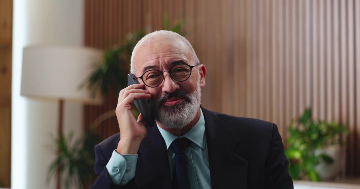 Uomo d'Affari Maturo che Parla allo Smartphone in un Ufficio Moderno