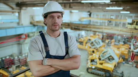 portrait of factory worker in hardhat standing in industrial warehouse