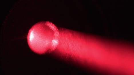 primer plano de un puntero láser disparando un haz de partículas de luz roja
