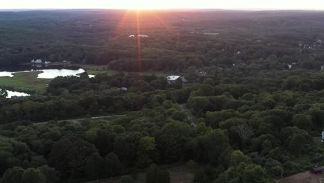 reverse aerial shot over rural area of the northeastern usa at summer sunset, with lens flare