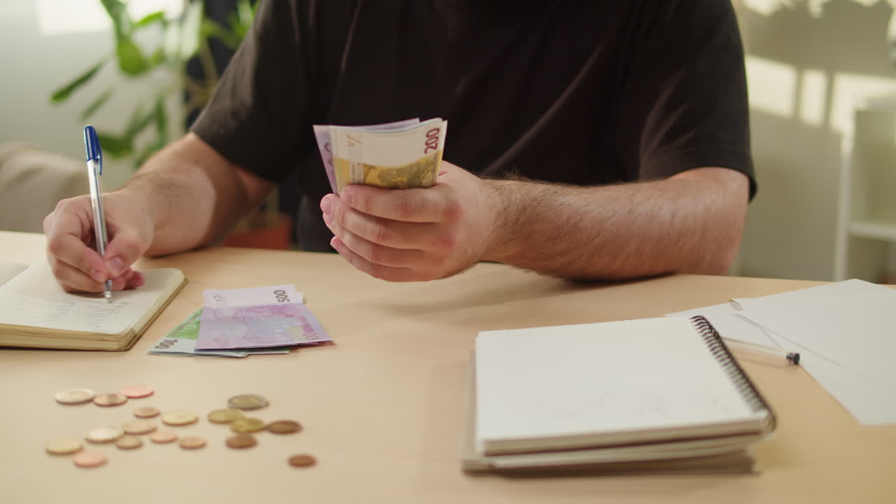 Persona che conta banconote in euro e scrive in un quaderno