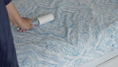 woman using a lint roller on a bed