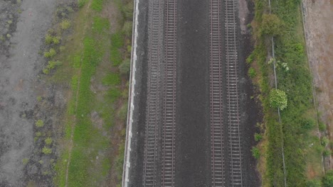passenger train passing by on the railway at the countryside in county kildare, ireland - aerial top view