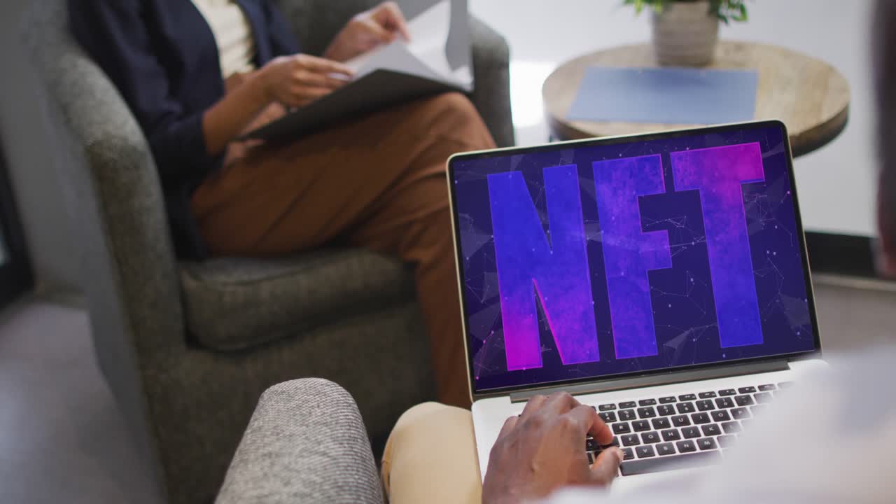 hombre de negocios afroamericano usando portátil para videollamada con texto nft