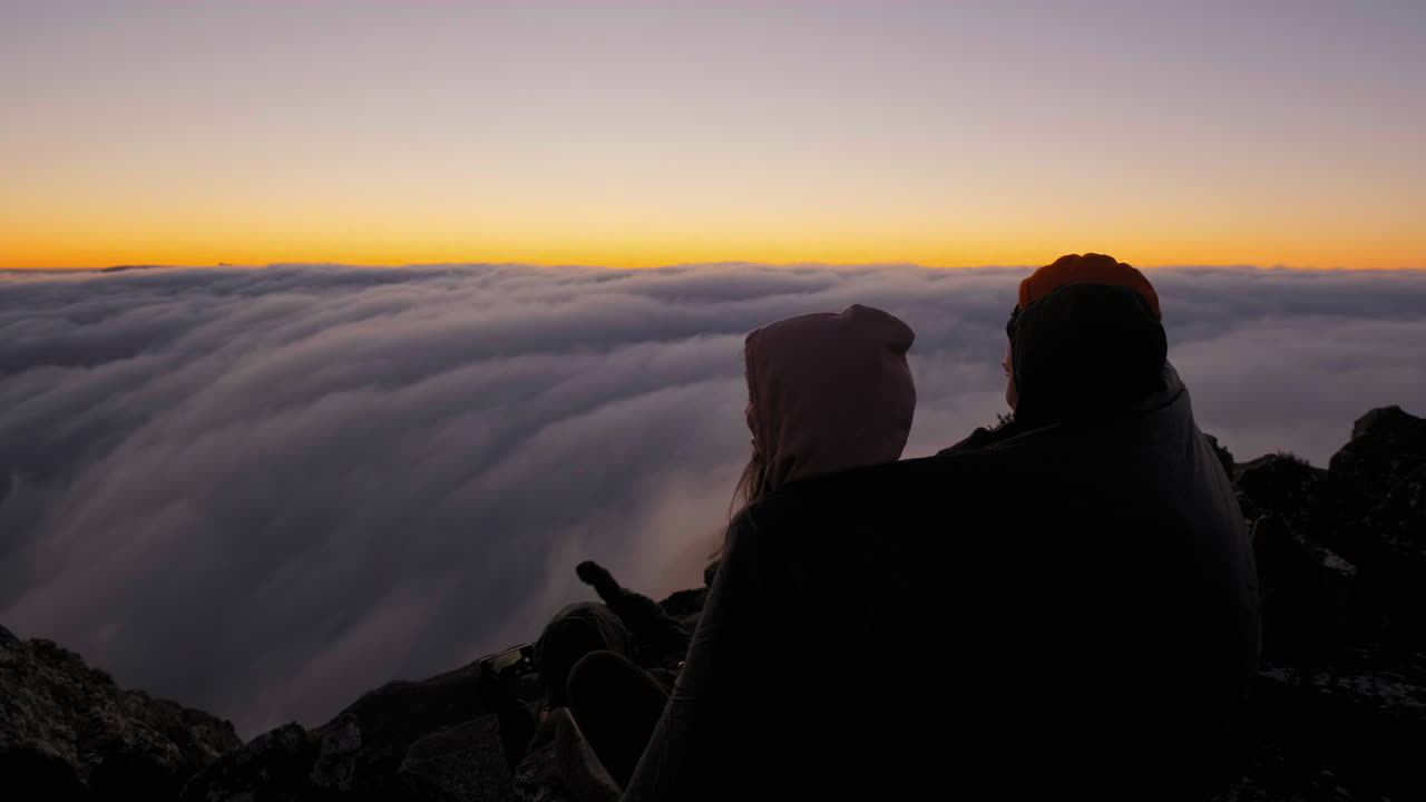 Hikers bonding and enjoying the dusk, above clouds on Mount Hassell, in West Australia