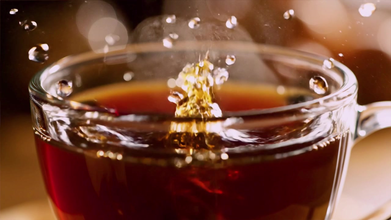 湯気の立つガラス製コーヒーカップに落ちる焙煎されたコーヒー豆