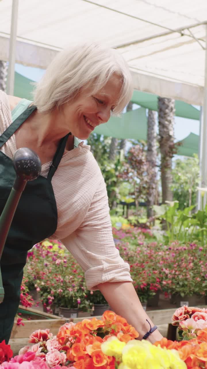 여성 이 온실 에서 꽃 에 물 을 주고 있다
