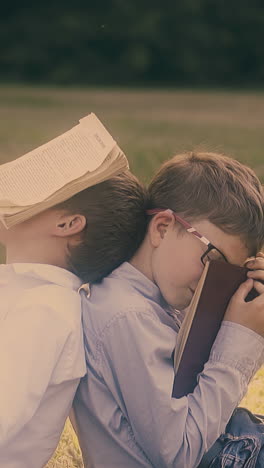 young exhausted schoolboys sleep with textbooks on face preparing for difficult exam close view slow motion
