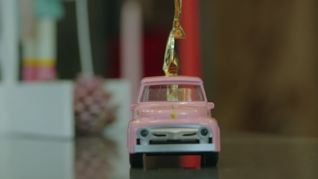 Close-Up of a Pink Toy Truck Topped with a Shiny Golden Accent