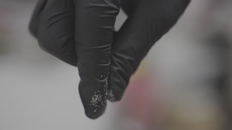 Adding-salt-to-food,-closeup-on-chef's-fingers-in-black-glove