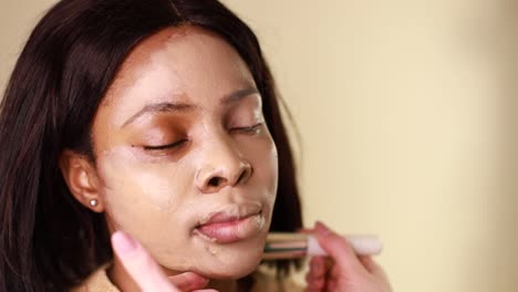 a female makeup artist applying gold makeup to a black african-american model. the concept of beauty and makeup