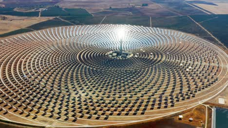 solar panels in a large thermal circular power plant with the reflection of the sunlight in the panels. renewable and pollution-free energy in a solar farm in spain- aerial view with a drone - environmental concept