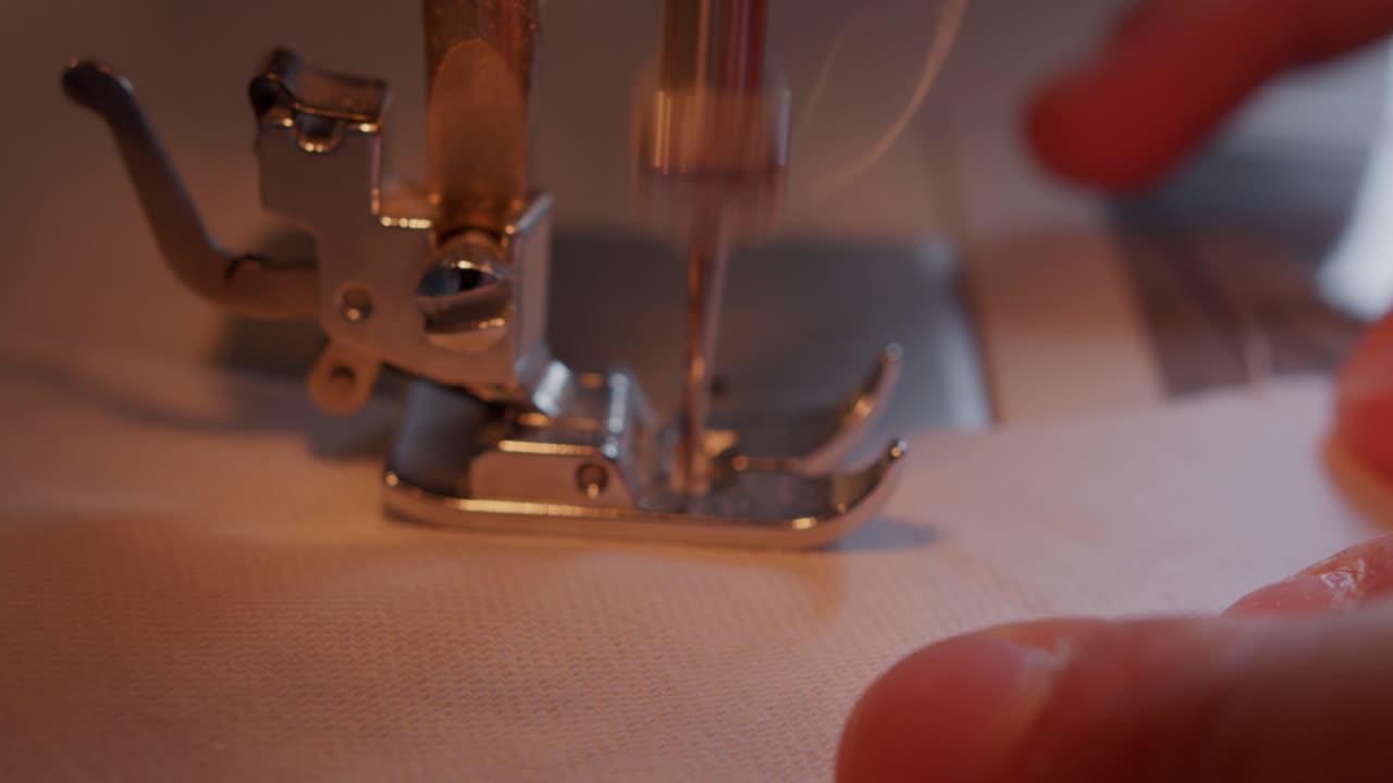 primer plano del pie y la aguja de la máquina de coser en funcionamiento con los dedos guiando el tejido