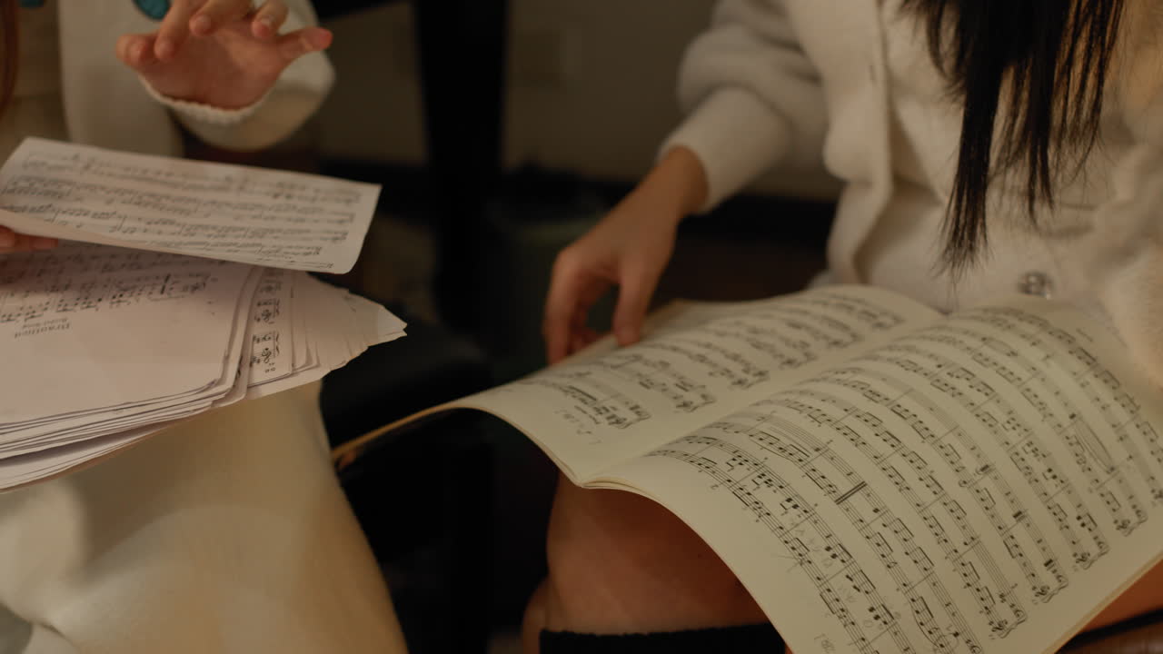 두 소녀 는 손가락 으로 세부 사항 을 지적 하여 음악 악보 를 공부 한다