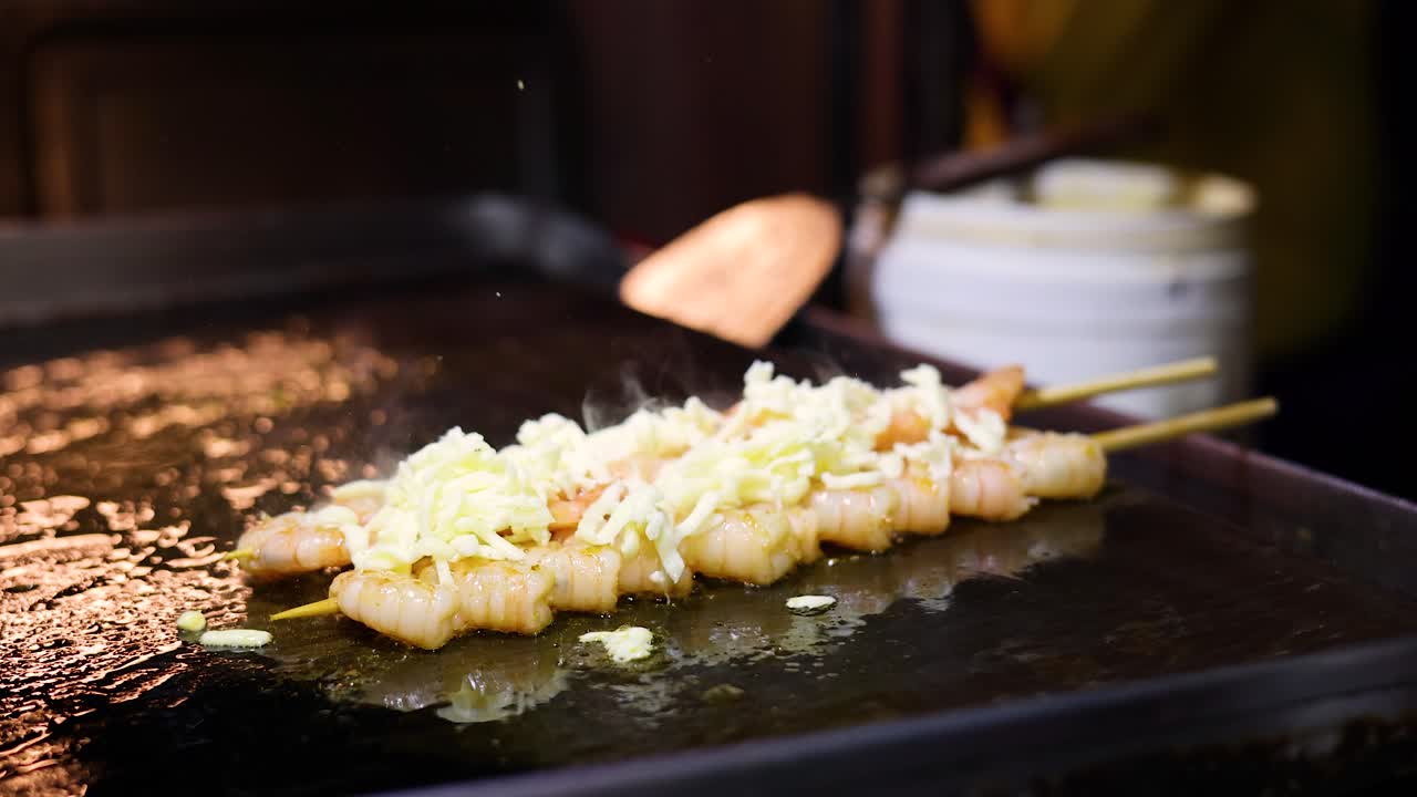 Spiedini di gamberi con formaggio grigliati su piastra, illuminazione calda e soffusa, primo piano di una scena di street food
