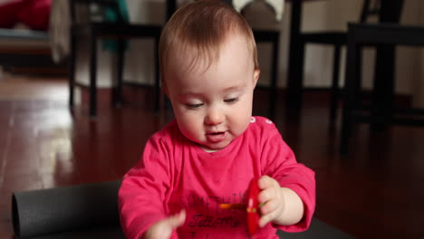 happy cute little baby plays in front of the camera with a wood toy, shot in slow motion