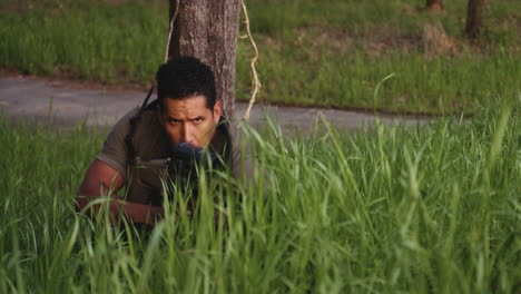 Tactical-soldier-aiming-rifle-in-tall-grass-at-dusk-in-Collierville,-Tennessee