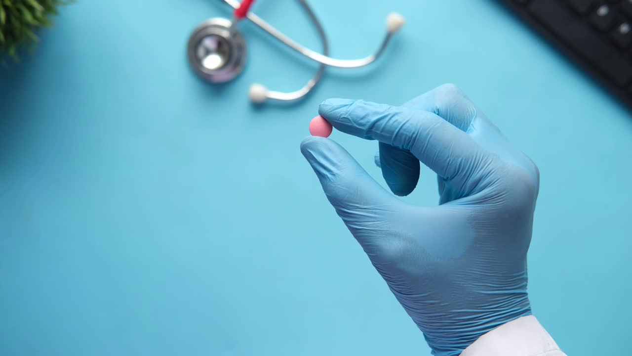 Professionista medico che tiene una pillola rosa