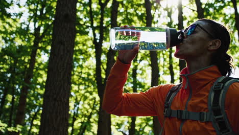woman hiking and drinking water in forest