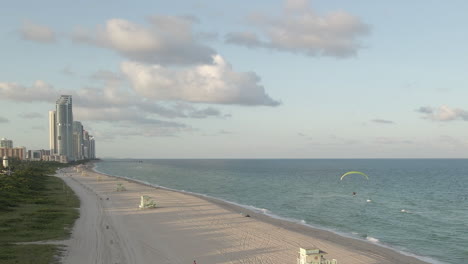 Hombre-En-Paramotor-Vuela-Sobre-La-Playa-De-Haulover-En-Una-Tarde-Tranquila-En-Miami