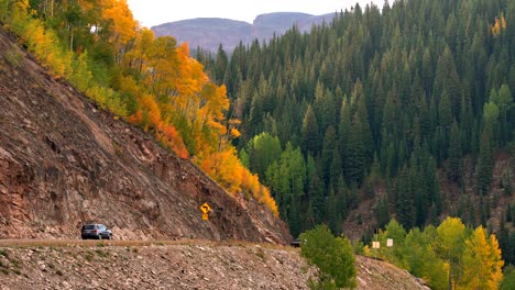 Car-going-through-a-canyon-a-valley-in-the-San-Juan-Mountains-of-Colorado-against-a-background-of-fall-colors